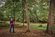 Photo of Craftsman pole saw CMECSP610 trimming tree branches outdoors in a wooded area.